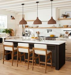 a kitchen island with four chairs in front of it