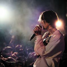 a woman singing into a microphone in front of a large group of people at a concert