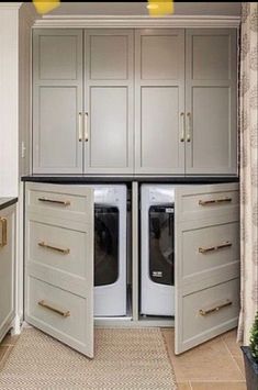 a washer and dryer are in the middle of a kitchen with white cabinets