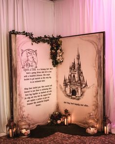 an open book sitting on top of a table next to candles and flowers in front of a castle