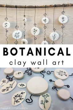 some white and black buttons are hanging from a string with the words botanical clay wall art