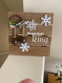 a wooden sign with snowflakes hanging from it's sides and the words ring