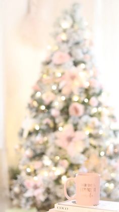 a coffee mug sitting on top of a stack of books next to a christmas tree