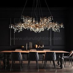 an elegant chandelier hangs over a dining room table with black chairs and dark walls