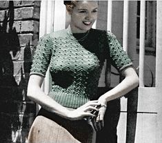 a black and white photo of a woman wearing a green dress with her hands in her pockets