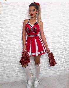 a woman in a cheerleader outfit holding pom poms and posing for the camera