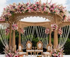 an outdoor wedding set up with pink flowers and greenery on the top of it