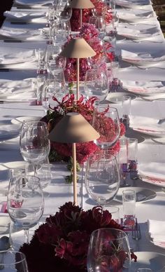 a long table is set with wine glasses and flowers