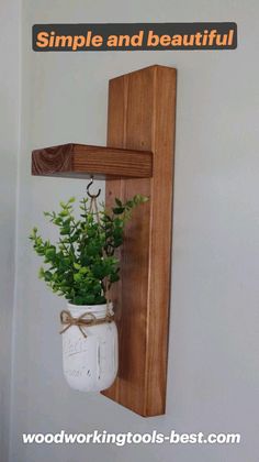 there is a plant in a mason jar hanging on the wall next to a wooden shelf