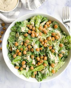 a white bowl filled with lettuce and chickpeas on top of a table