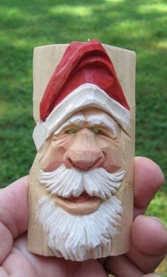 a hand holding a small wooden santa clause