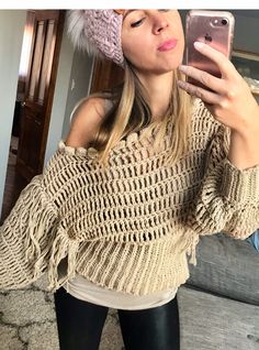 a woman taking a selfie while wearing a knitted sweater and black leggings