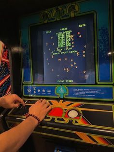 a person playing an old school video game with their hand on the button and writing