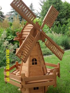 a wooden windmill sitting on top of a lush green field