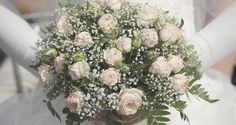 a bride holding a bouquet of white roses and baby's breath in her hands