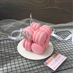 some pink macaroons are on a white plate with a silver heart shaped decoration