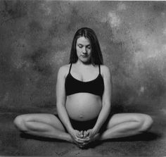 a pregnant woman sitting in the middle of a yoga pose