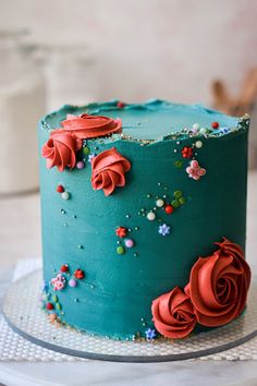 a blue cake with red flowers on it