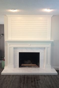 an empty fireplace with white paint and wood flooring