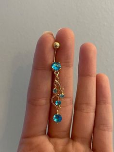 a person is holding up a gold ring with blue stones on the bottom and an ear chain