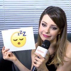 a woman holding up a sign with a smiley face on it and a microphone in front of her