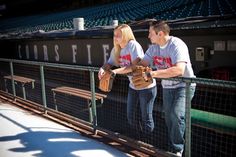 two people standing next to each other in front of a baseball dugout at a stadium