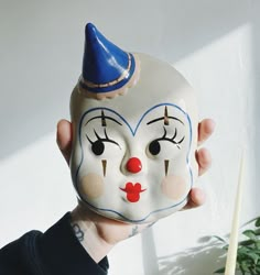 a person holding up a white mask with a blue hat on it