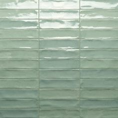 a green tile wall that has been painted in shades of blue and white, with the light reflecting off it's surface