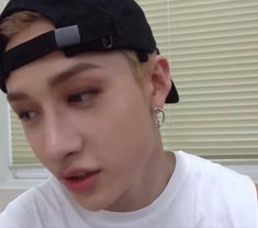 a young man wearing a black hat and hoop earrings