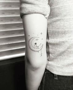 a person with a small tattoo on their arm and the moon behind them is shown