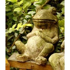 a frog statue sitting on top of a wooden bench