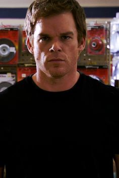 a man standing in front of a wall with records on it's sides and looking at the camera