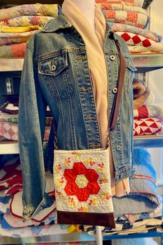 a denim jacket is hanging on a rack in front of quilts and other fabrics