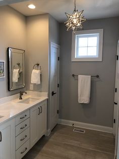 a bathroom with two sinks, mirrors and towels hanging on the rack in front of it