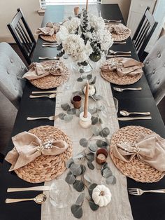 a dining room table set with place settings, napkins and flowers in vases