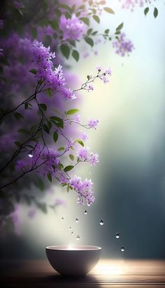 a bowl with purple flowers in it sitting on a table next to a tree branch