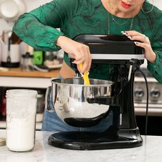 a woman mixing something in a bowl on top of a counter