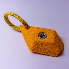 a yellow keychain with a metal button on it's end and a cord attached to it