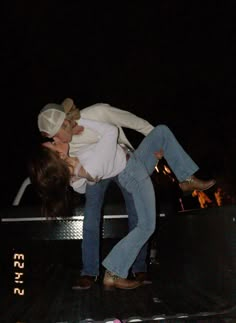 two people on the back of a truck at night with their arms around each other