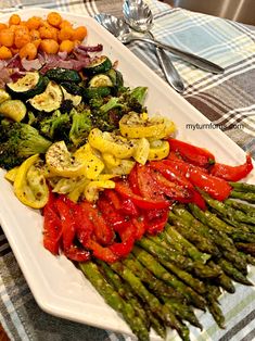 asparagus, tomatoes, broccoli and other vegetables on a white platter