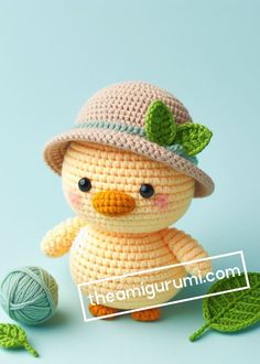 a crocheted stuffed animal wearing a hat and holding a ball of yarn