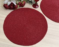 two red round rugs sitting on top of a wooden floor next to vases with flowers