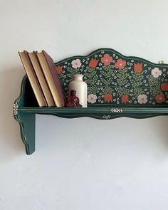 a green shelf with books and vases on it