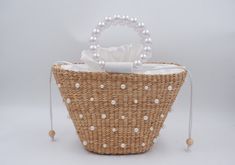 a straw bag with white pearls on the handle