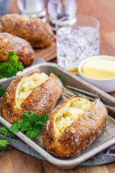 bread rolls with cheese and parsley on a tray next to butter, sauces and water