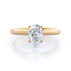 a yellow gold ring with a pear shaped diamond