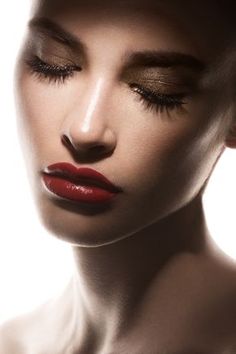 a woman with her eyes closed wearing red lipstick and eyeliners is posing for the camera