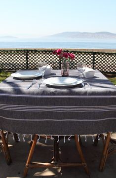 the table is set with plates and silverware on it, overlooking the ocean in the distance