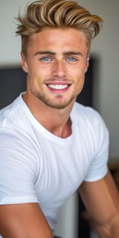 a man with blonde hair and blue eyes smiles at the camera while wearing a white t - shirt