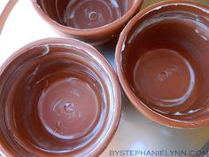 three brown bowls filled with chocolate on top of a table